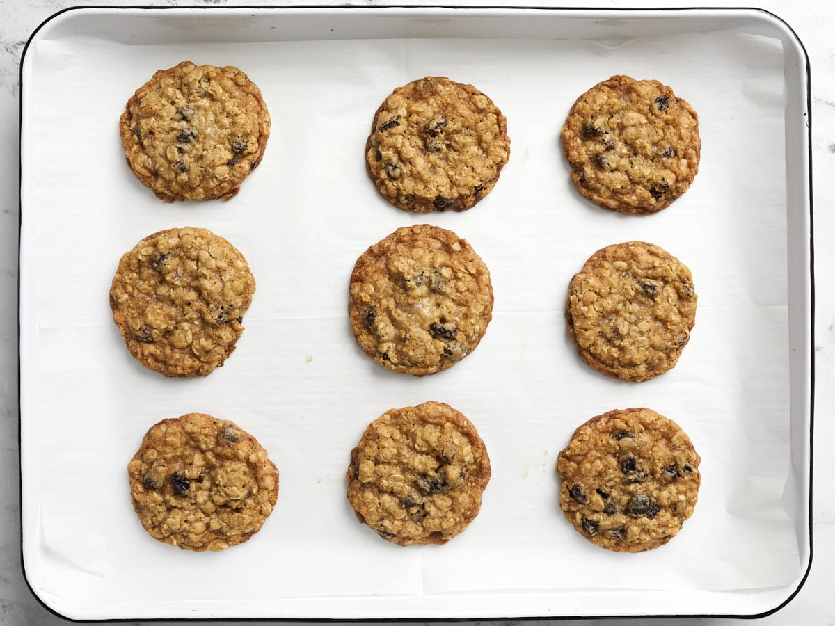 Baked oatmeal raisin cookies on a parchment lined baking sheet.