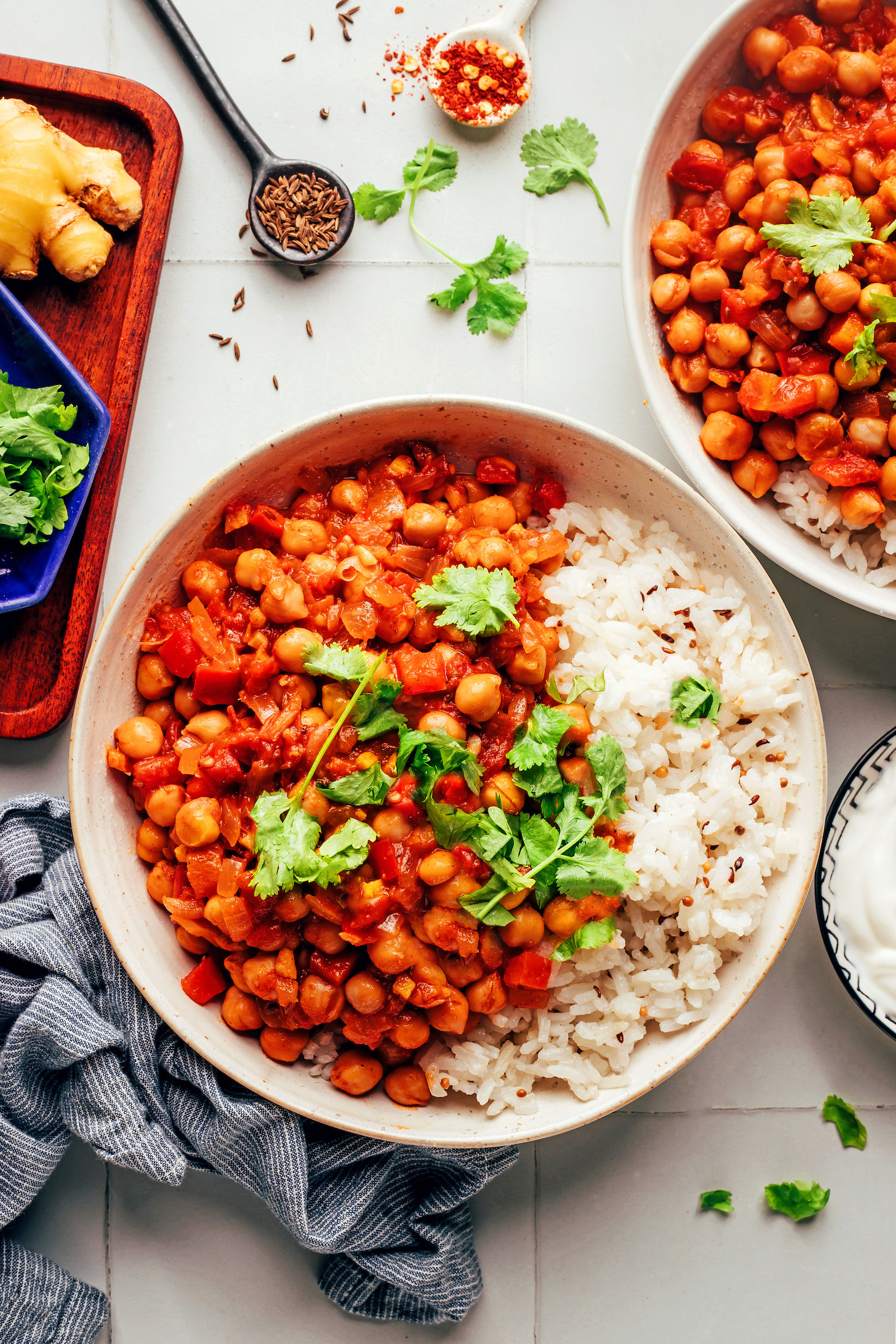Two bowls of vindaloo-inspired vegan chickpea curry with jeera rice and cilantro