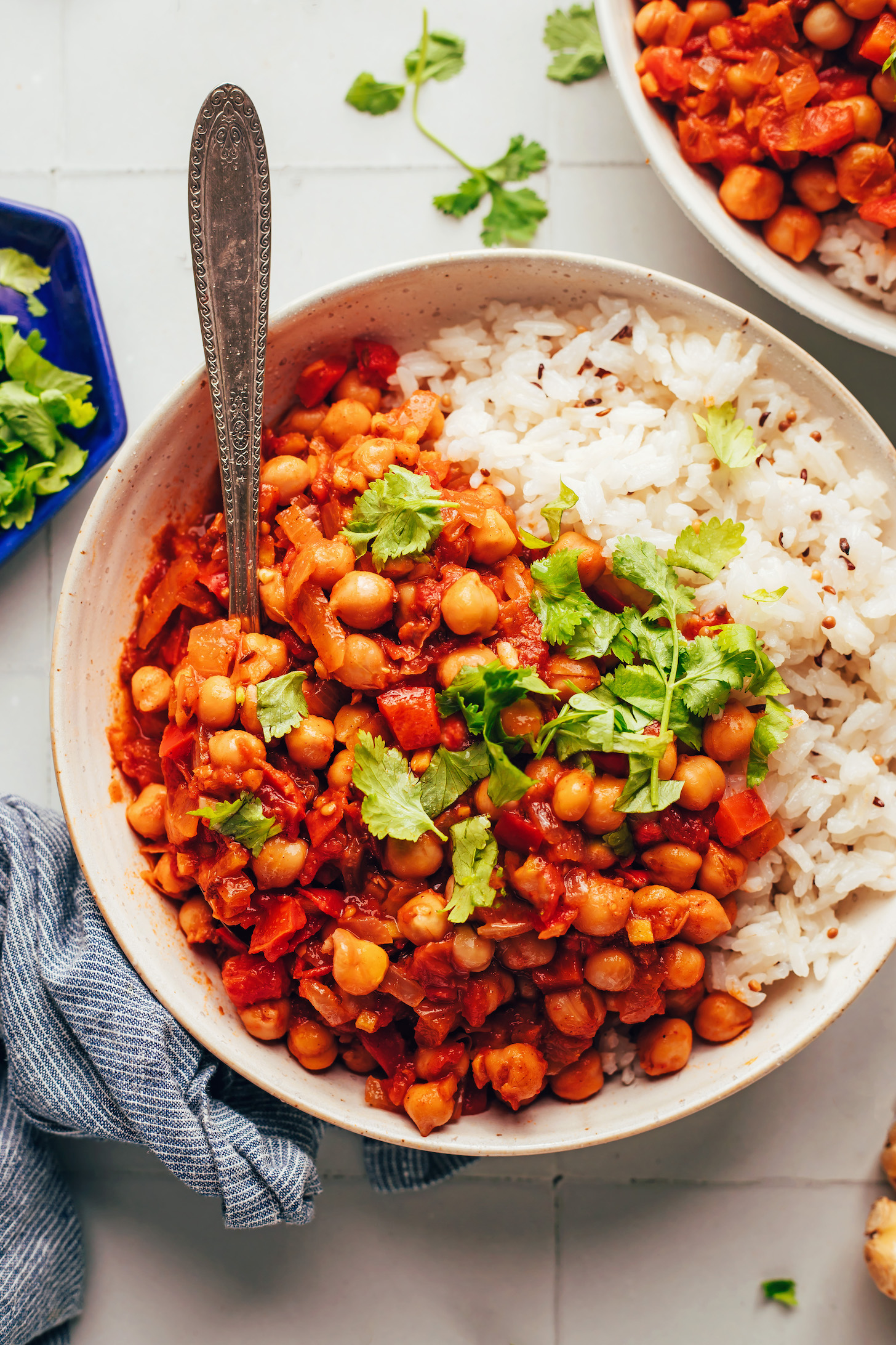Overhead shot of a bowl of jeera rice and warming vegan chickpea curry topped with cilantro