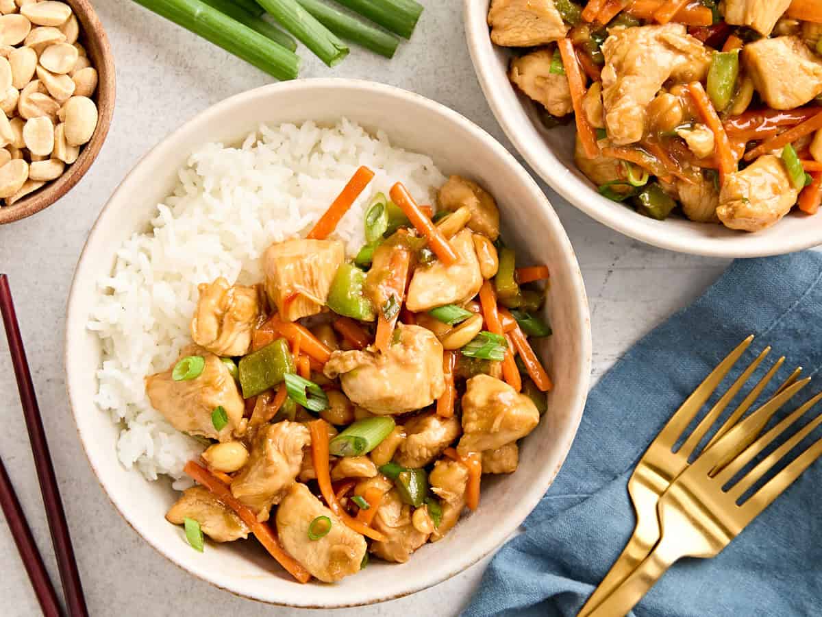 Overhead view of two bowls of kung pao chicken with rice.