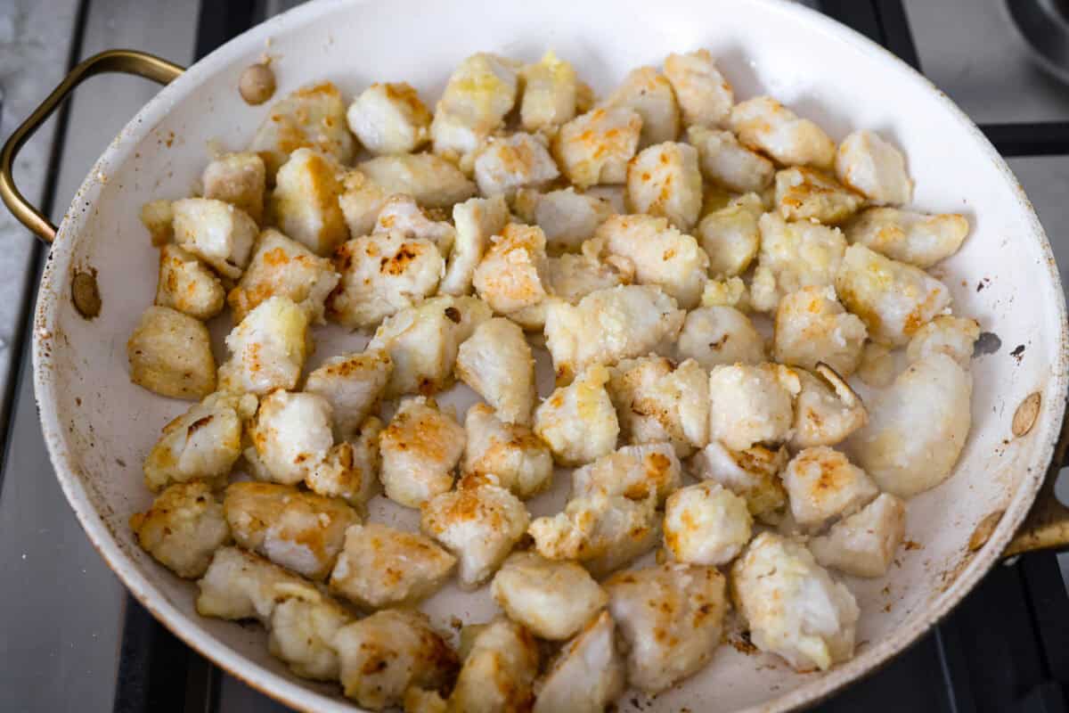 Chicken pieces being pan fried on the stove top.