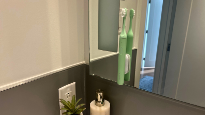 Green electric toothbrush hanging on mirror in bathroom