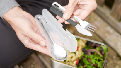 Hand holding portable silverware set over food