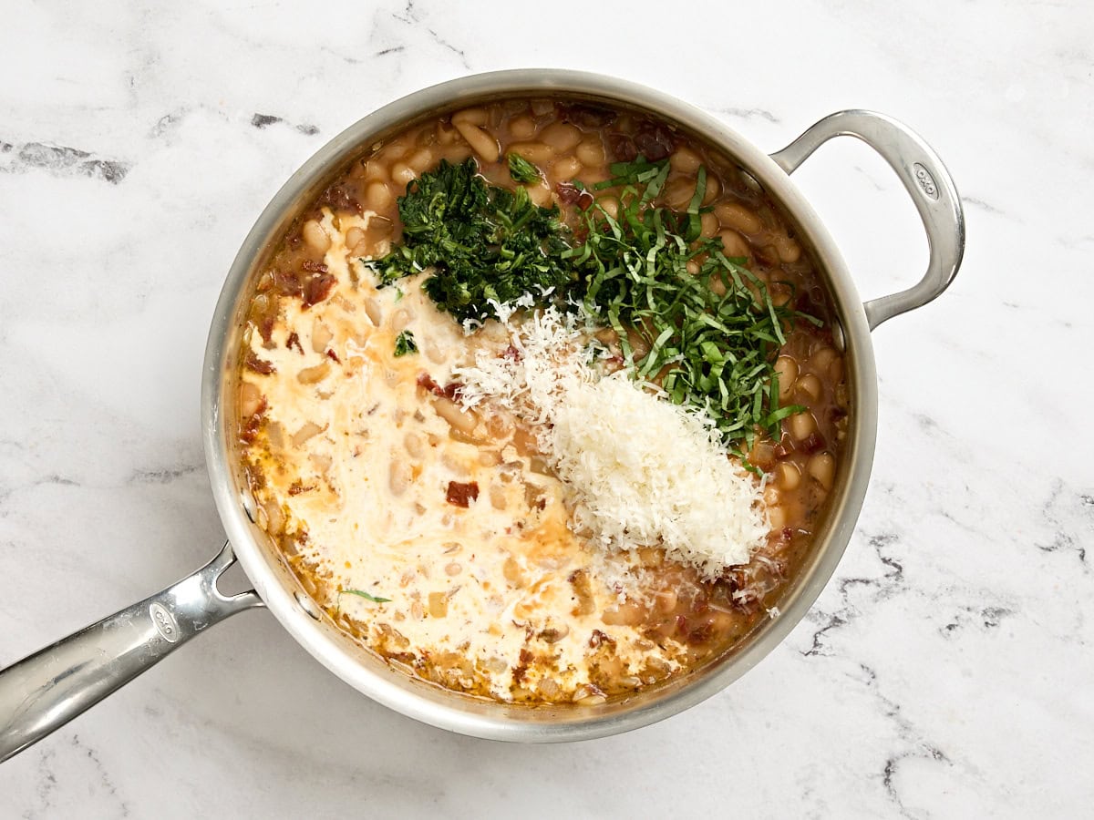 Cream, cheese and spinach added to a skillet of white beans.