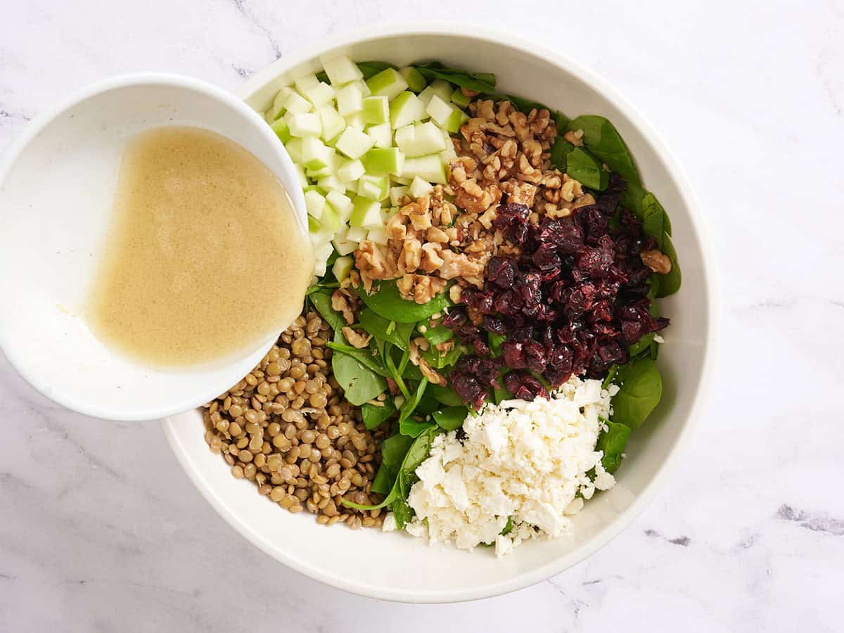 A homemade vinaigrette being poured into a lentil salad.