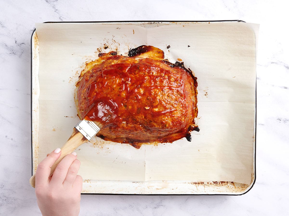 Brushing the meatloaf with glaze after 40 minutes of baking.