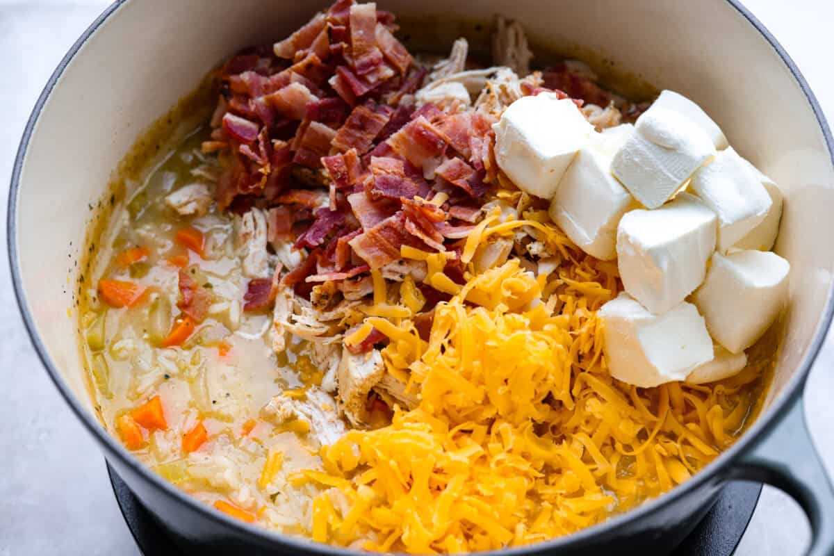 Stop what you are doing right now, and make this Crack Chicken and Rice soup! With tender chicken, rice, creamy cheese, crispy bacon, and bold ranch flavor, this easy one pot recipe tastes like pure comfort in every spoonful. Cream cheese, bacon and cheese added to the crack chicken and rice soup.