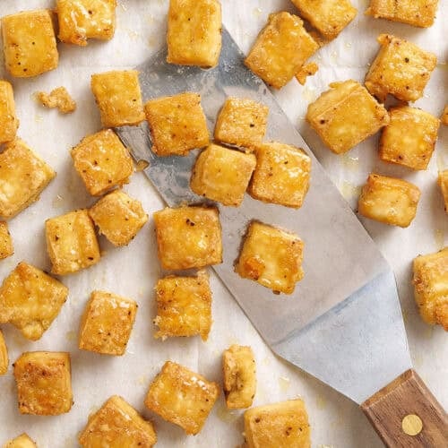 Overed view of baked tofu being scooped with a spatula.