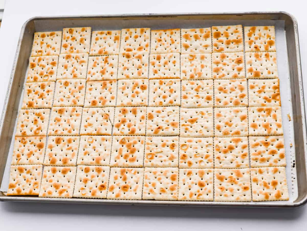 My Valentine’s Day Crack is the cutesy pink version of my famous Christmas crack! Same buttery, snappy toffee base, just with pink candy melts and festive sprinkles. It's perfect for kids' parties, Galentine's, or a sweet little Valentine's treat. Saltines spread out on a cookie sheet.