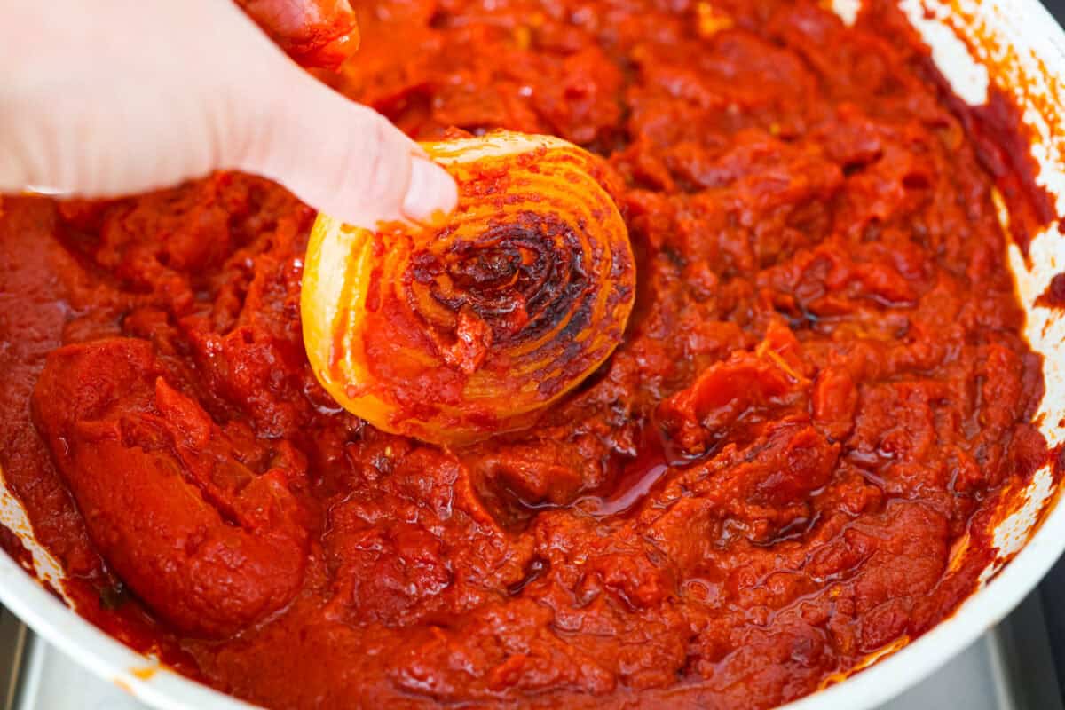 Someone taking the onions out of the sauce.