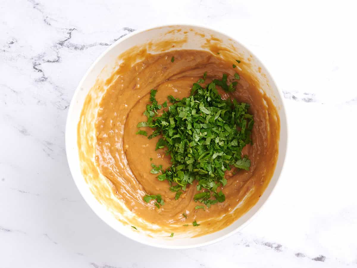 Cilantro added to peanut sauce in a bowl.