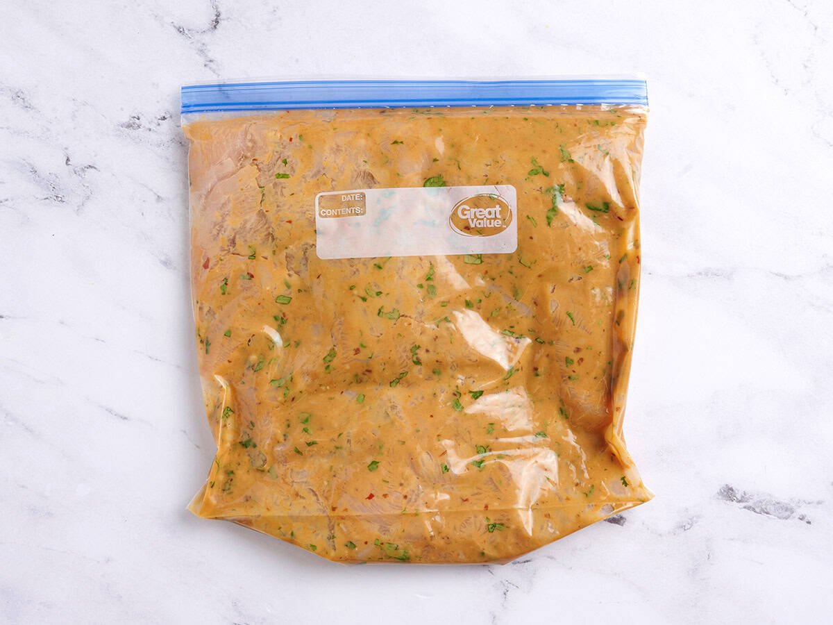 Chicken pieces marinated in a peanut sauce in a ziplock bag.