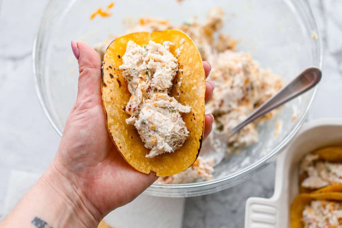 Someone filling the tortillas with crack chicken mixture.