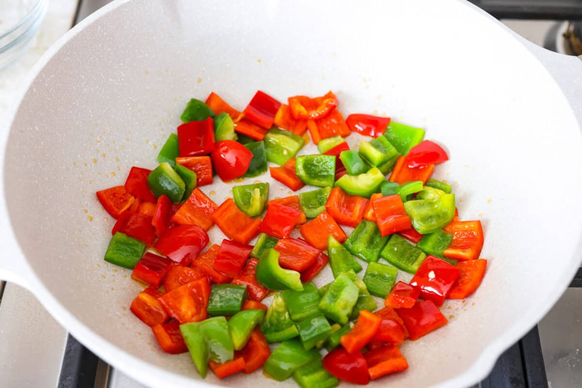 Wok with green and red bell peppers cooking.