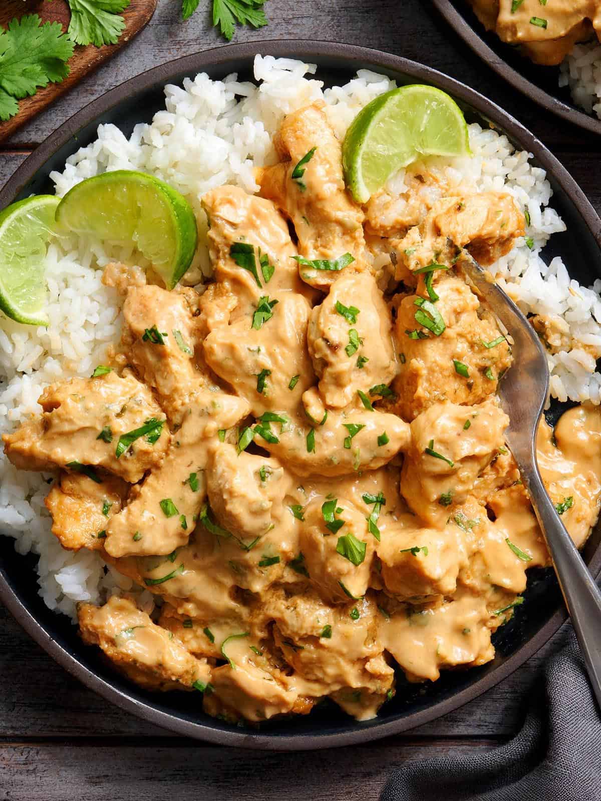 Overhead view of thai peanut chicken on a plate with white rice and lime rice.