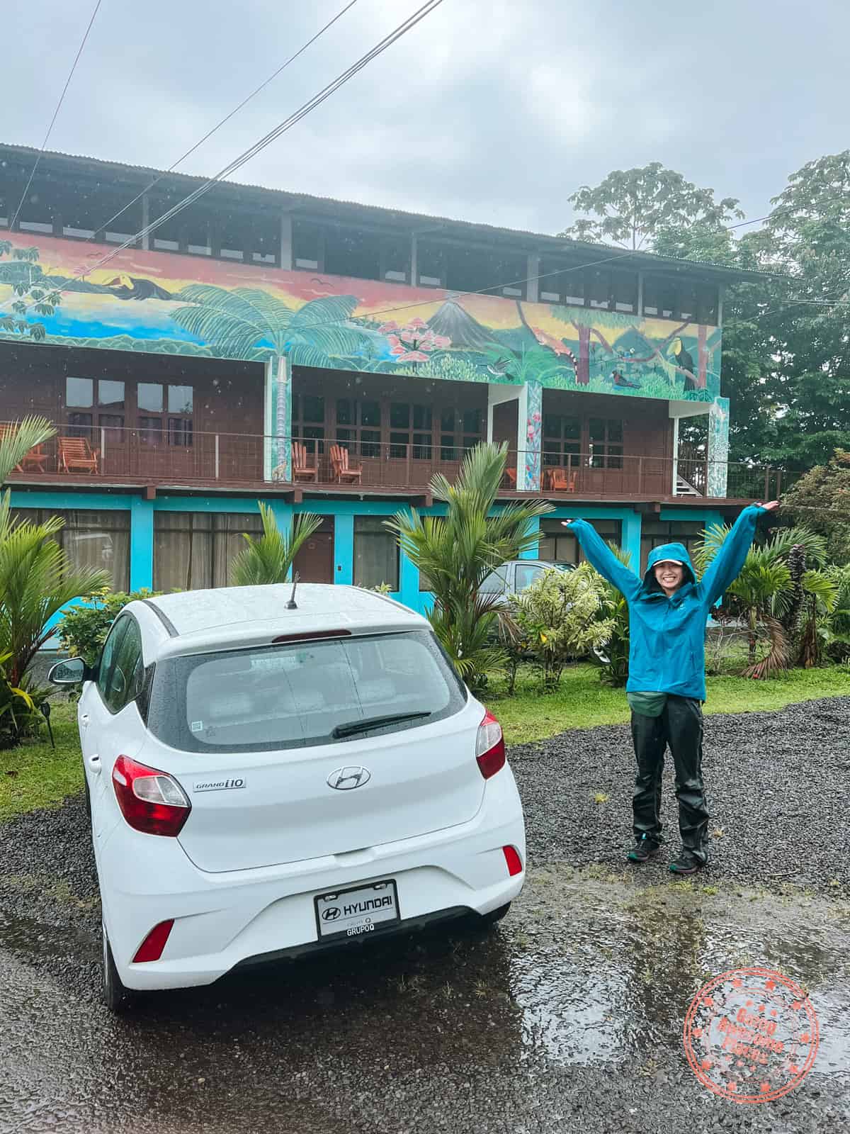 chantelle with car on a rainy day with hotel xilopalo arenal suites building