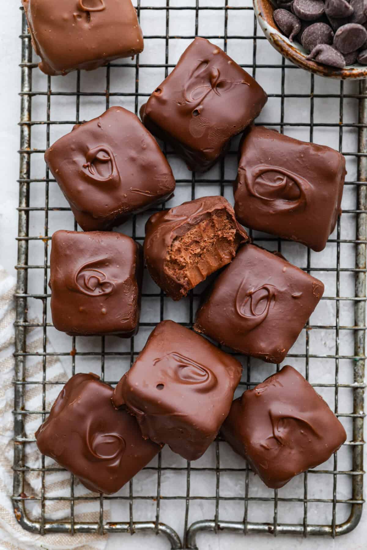 Cool whip candy pieces on a cooling rack with one on its side with a bite taken out.
