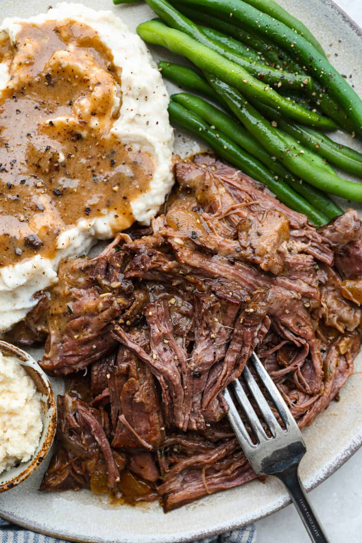 Plate of horseradish pot roast with green beans and mashed potatoes.