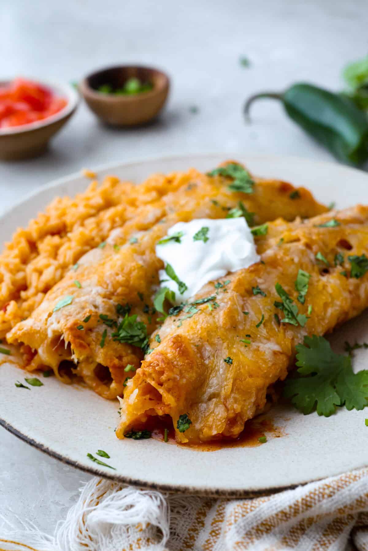 When you want enchiladas without the work, these Lazy Enchiladas are it! Four ingredients. Less than 30 minutes. Just layer frozen taquitos with beans, sauce, and cheese, bake until bubbly, and boom, dinner is served! Plated lazy enchiladas topped with sour cream and cilantro.