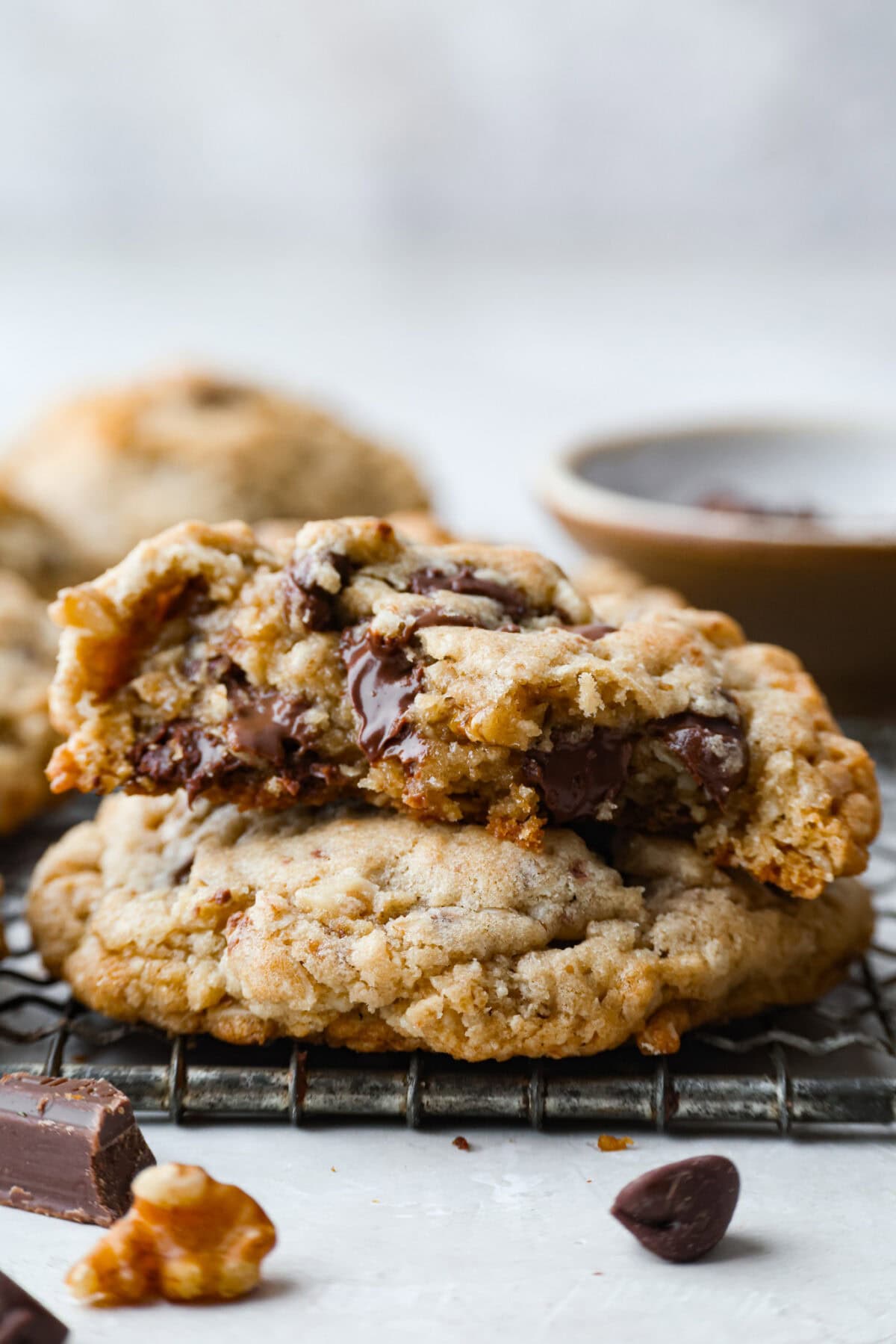 These Neiman Marcus Chocolate Chip Cookies come with a famous backstory, but the real star is the cookie itself. Thick, chewy, and packed with oats, two kinds of chocolate, and crunchy walnuts, they’re truly worth the hype. Side shot of stacked Neiman Marcus chocolate chip cookies, where the top on is cut in half and soft chocloate is melting over.