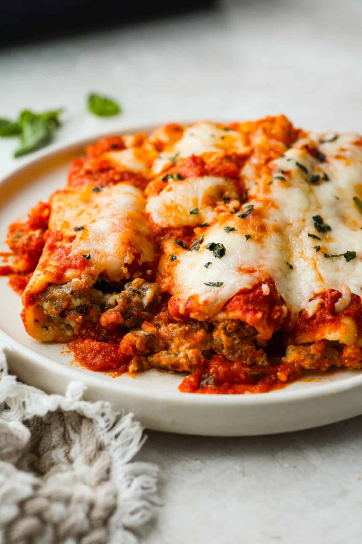 Plated sausage manicotti covered in melty cheese.