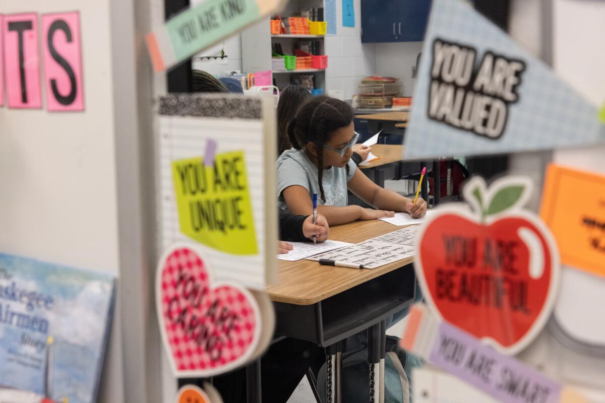 Halle O'Brien writes during after-school cursive club, held by teacher Sherisse Kenerson, at Holmes Middle School in Alexandria, Va.