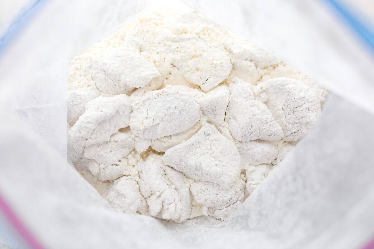Chicken pieces coated in cornstarch in a zip lock bag.