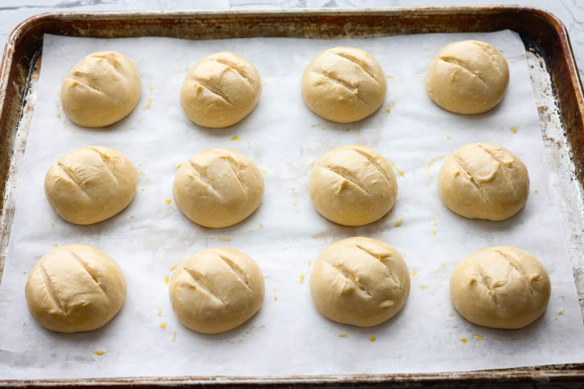 French bread dough balls scoured and covered in an egg wash, ready to go in the oven.