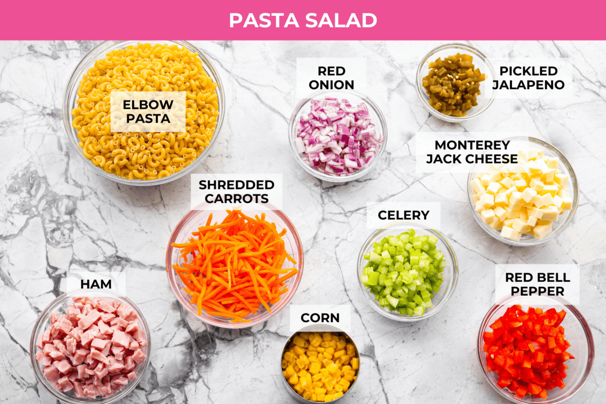 This Mexican macaroni salad is a fun twist on a classic! It’s creamy, tangy, and full of flavor with crisp veggies, cheese, and a little kick from jalapeños. Perfect for BBQs, potlucks, or anytime you want an easy, delicious side. Overhead shot of labeled pasta salad ingredients.