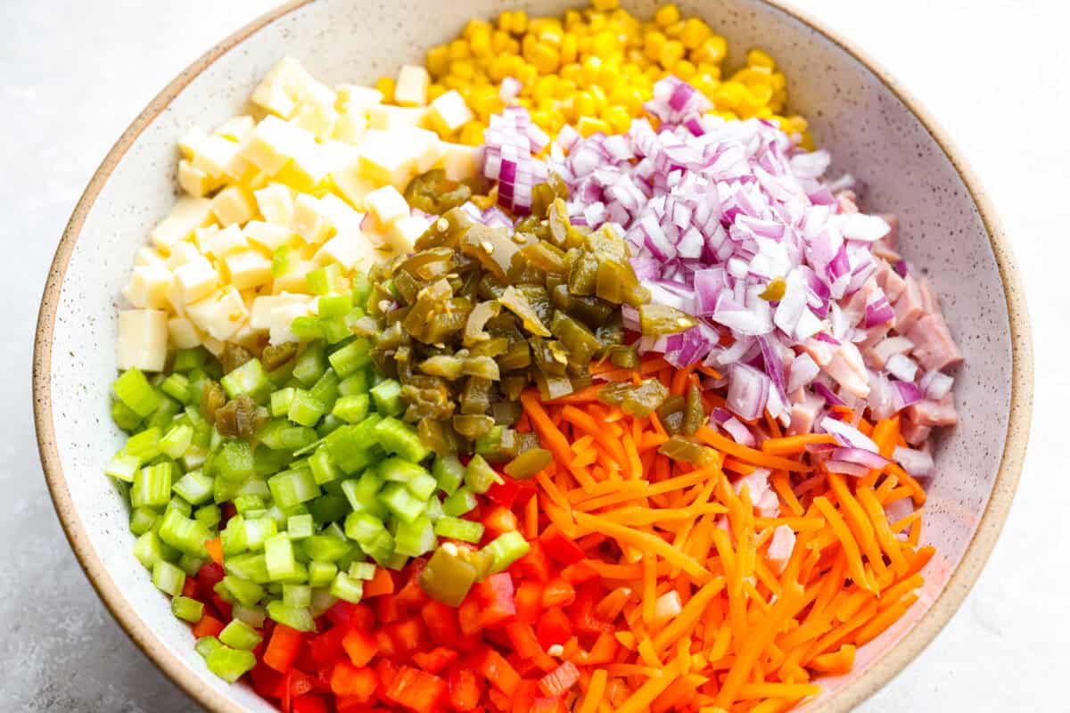 This Mexican macaroni salad is a fun twist on a classic! It’s creamy, tangy, and full of flavor with crisp veggies, cheese, and a little kick from jalapeños. Perfect for BBQs, potlucks, or anytime you want an easy, delicious side. All of the cheese, veggies and other ingredients in a bowl that go in the salad.