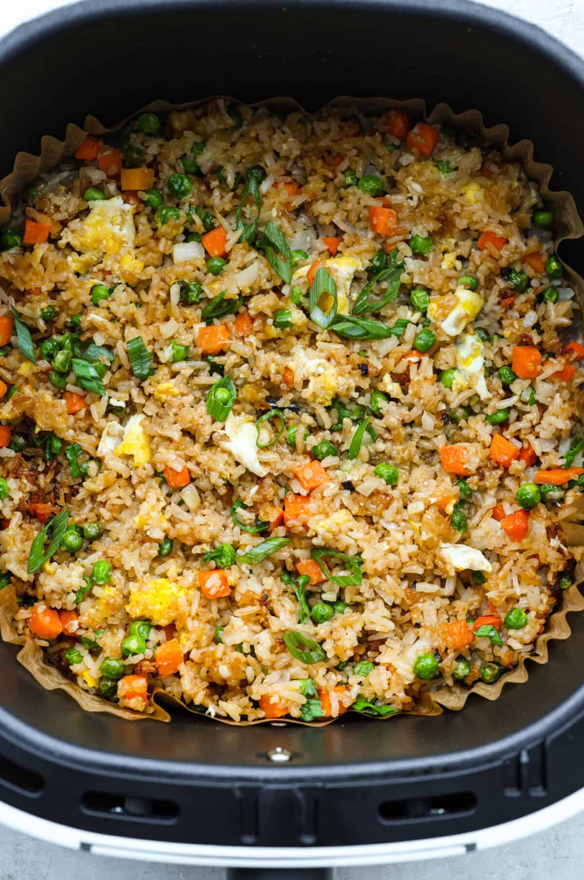 Did you know you can make fried rice in the air fryer? My Air Fryer Fried Rice recipe takes something already simple and makes it even easier. You get golden, slightly crispy rice, tender veggies, and the best flavor with hardly any effort. Overhead shot of fried rice in the air fryer basket.