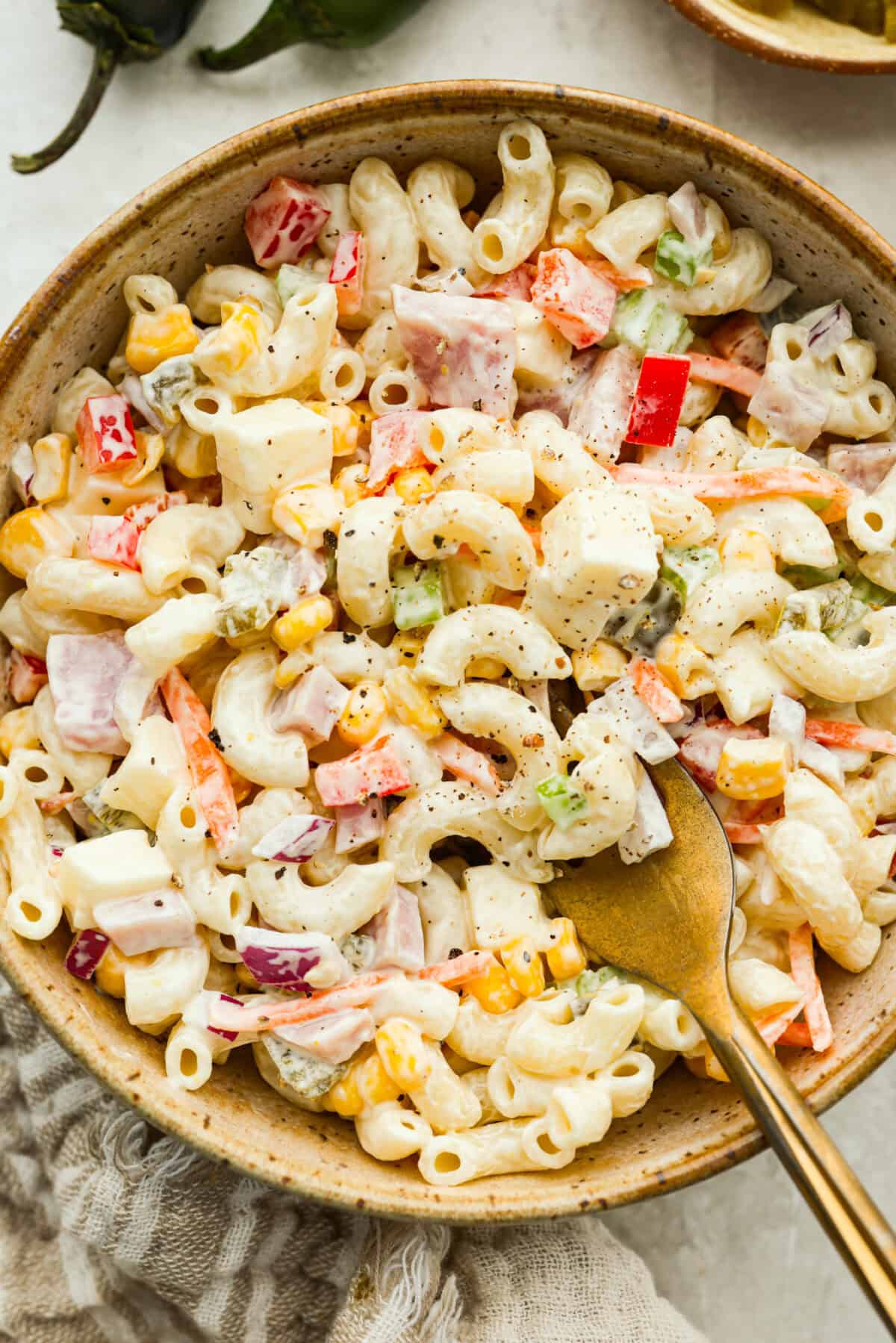 This Mexican macaroni salad is a fun twist on a classic! It’s creamy, tangy, and full of flavor with crisp veggies, cheese, and a little kick from jalapeños. Perfect for BBQs, potlucks, or anytime you want an easy, delicious side. Serving of Mexican macaroni salad in a bowl with a gold fork.
