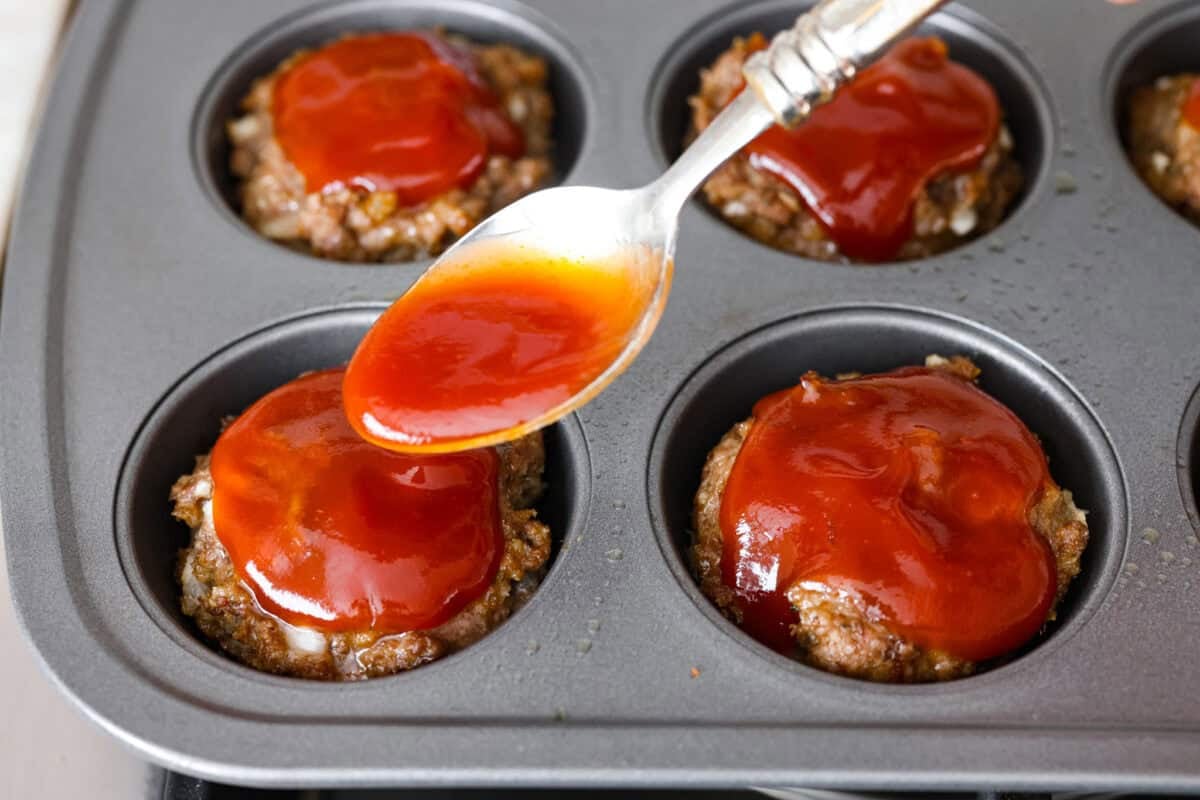 Glaze being spooned over the mini meatloaf muffins.