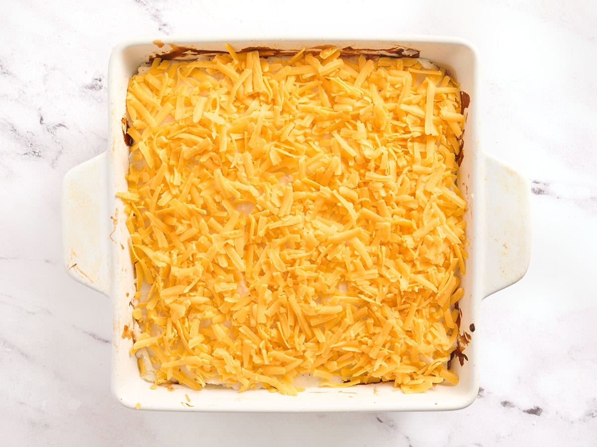 A meatloaf casserole topped with shredded cheddar cheese.