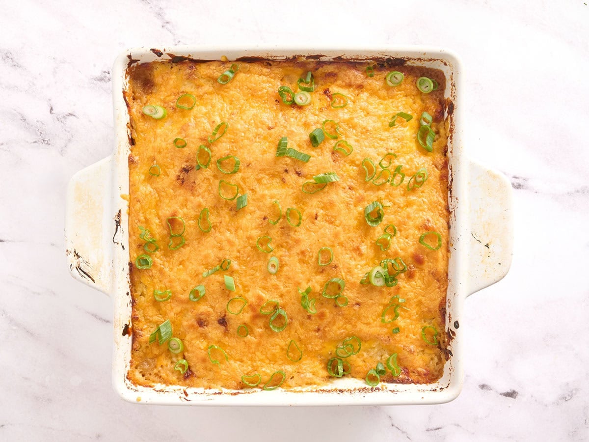 Meatloaf casserole after baking in the oven, covered in melted cheese and sliced green onions.