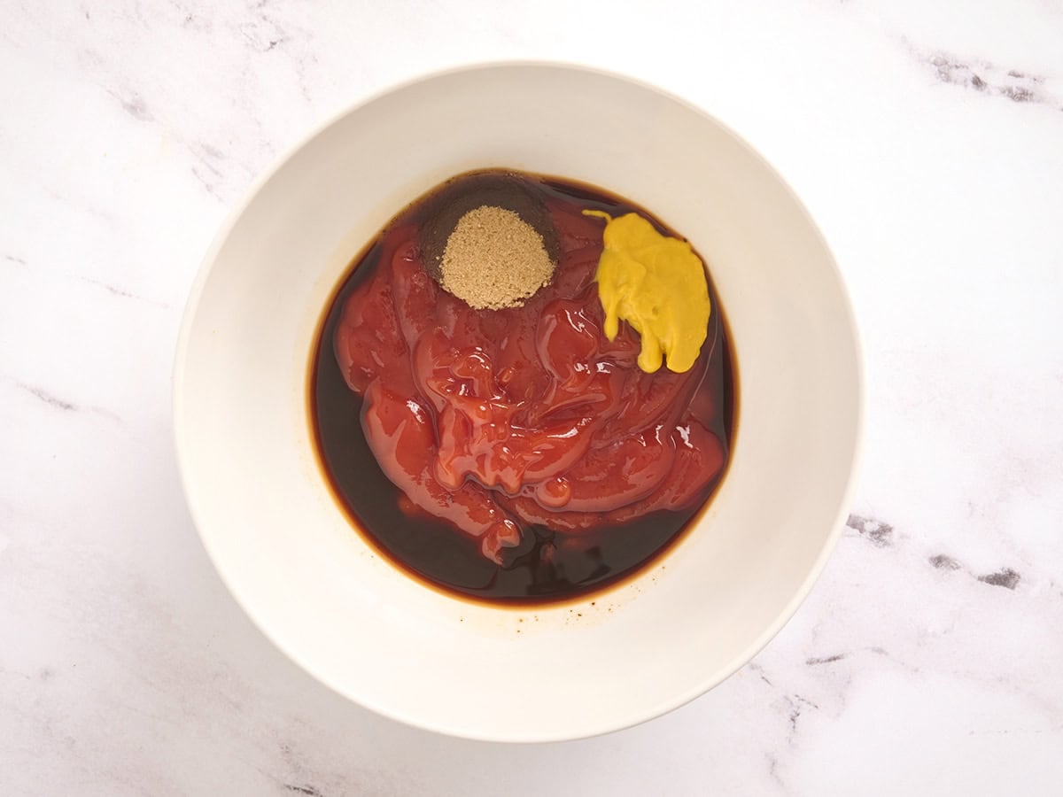 Ketchup, mustard, worcestshire sauce, and brown sugar in a mixing bowl.