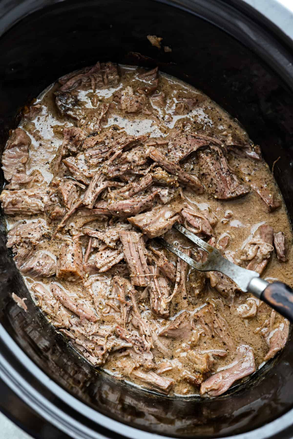 Shredded up 4 ingredient mushroom beef in a crockpot.