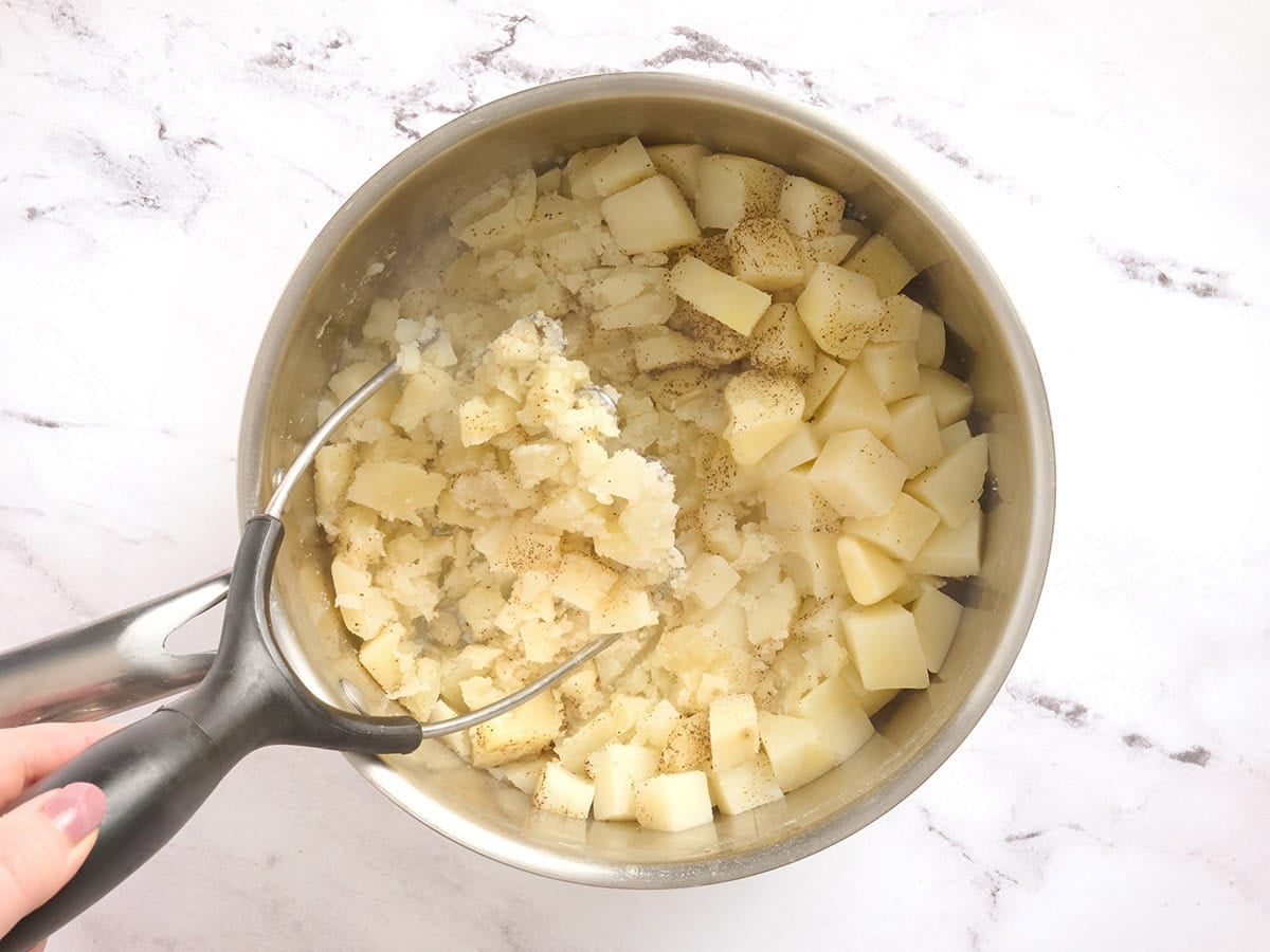 A potato mashed mashing potatoes in a pot.