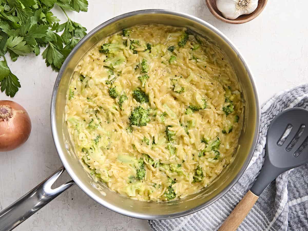 Overhead view of creamy broccoli cheddar orzo in a skillet.