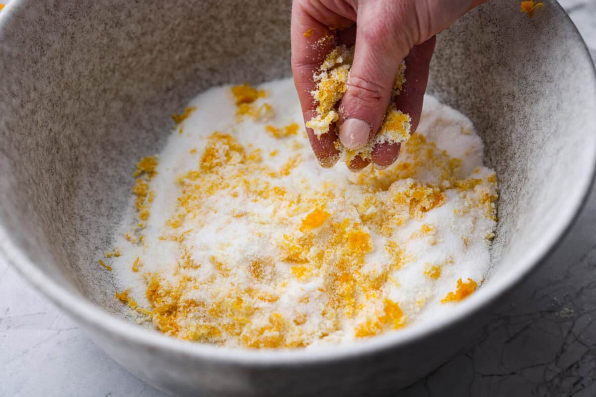 Someone rubbing the orange zest into the sugar.