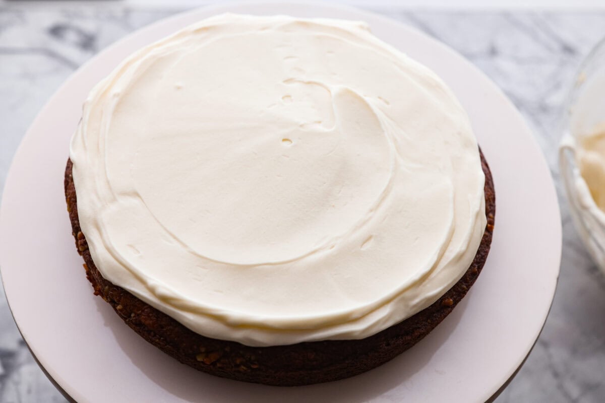 First layer of hummingbird cake with a layer of frosting on top.