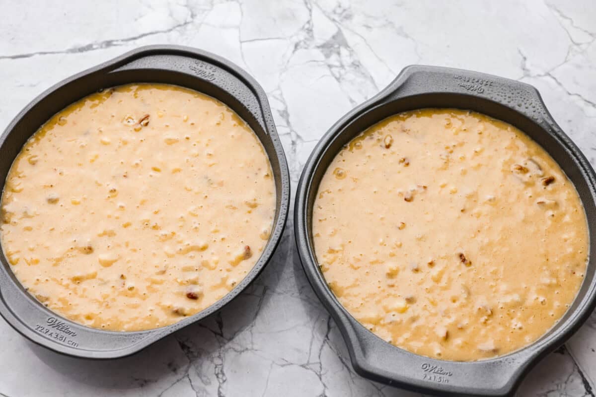 Two round cake pans filled with batter ready to go in the oven.