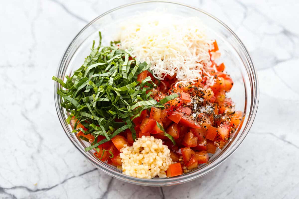 All of the tomato topping ingredients added to a bowl.
