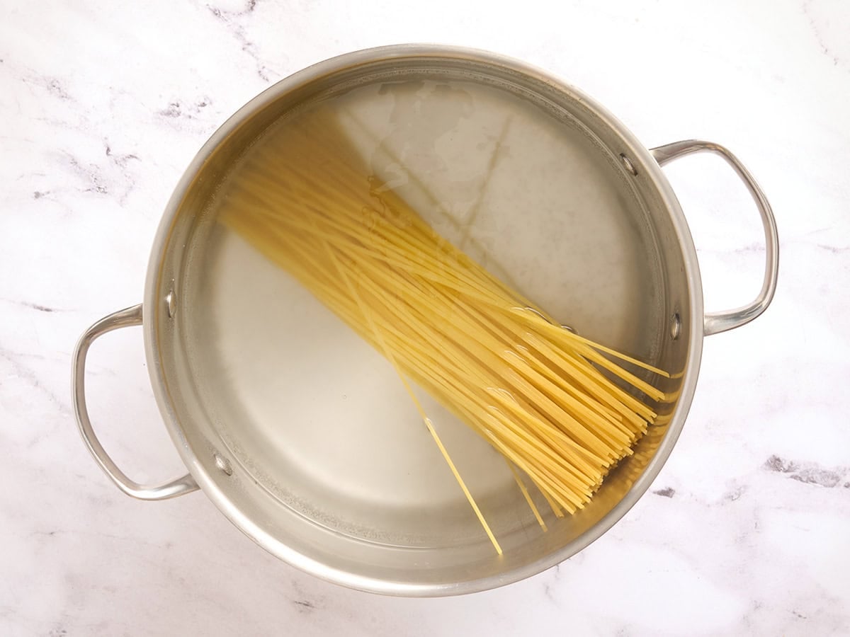 Spaghetti cooking in a sauce pan.