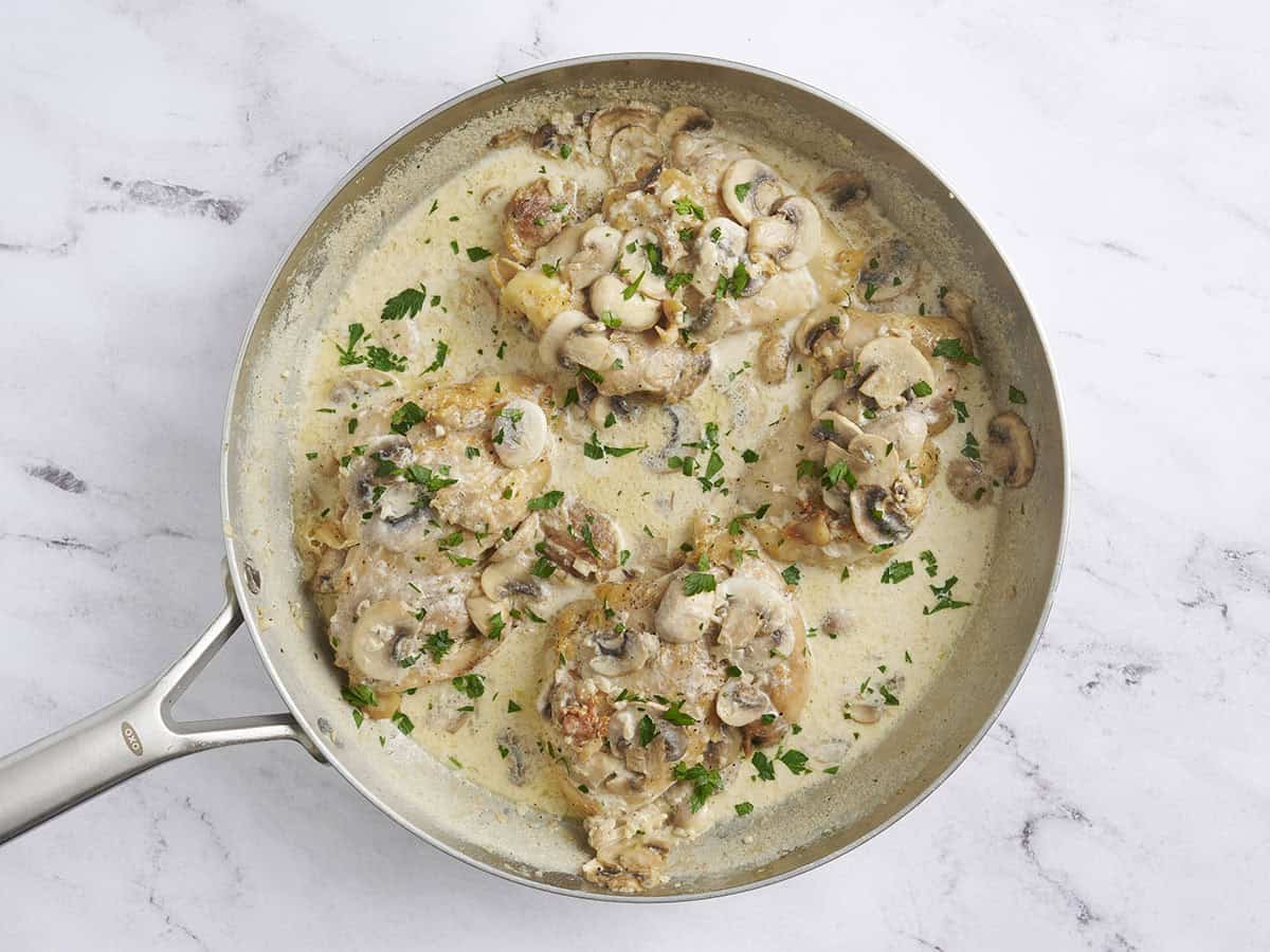 Creamy mushroom chicken in a skillet with parsley.
