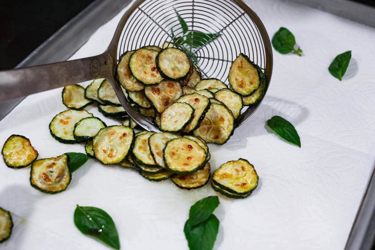 Spaghetti alla Nerano is an unforgettable pasta dish packed with flavor! It has a rich and creamy zucchini sauce infused with garlic, fresh basil, and melted cheese. Second photo of the pasta and basil placed on a sheet pan lined with paper towels.