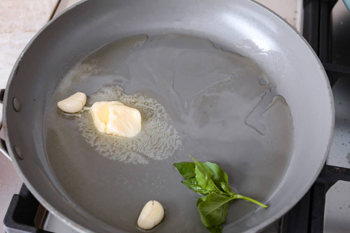 Spaghetti alla Nerano is an unforgettable pasta dish packed with flavor! It has a rich and creamy zucchini sauce infused with garlic, fresh basil, and melted cheese. Third photo of the garlic, butter, oil, and basil added to a hot skillet.