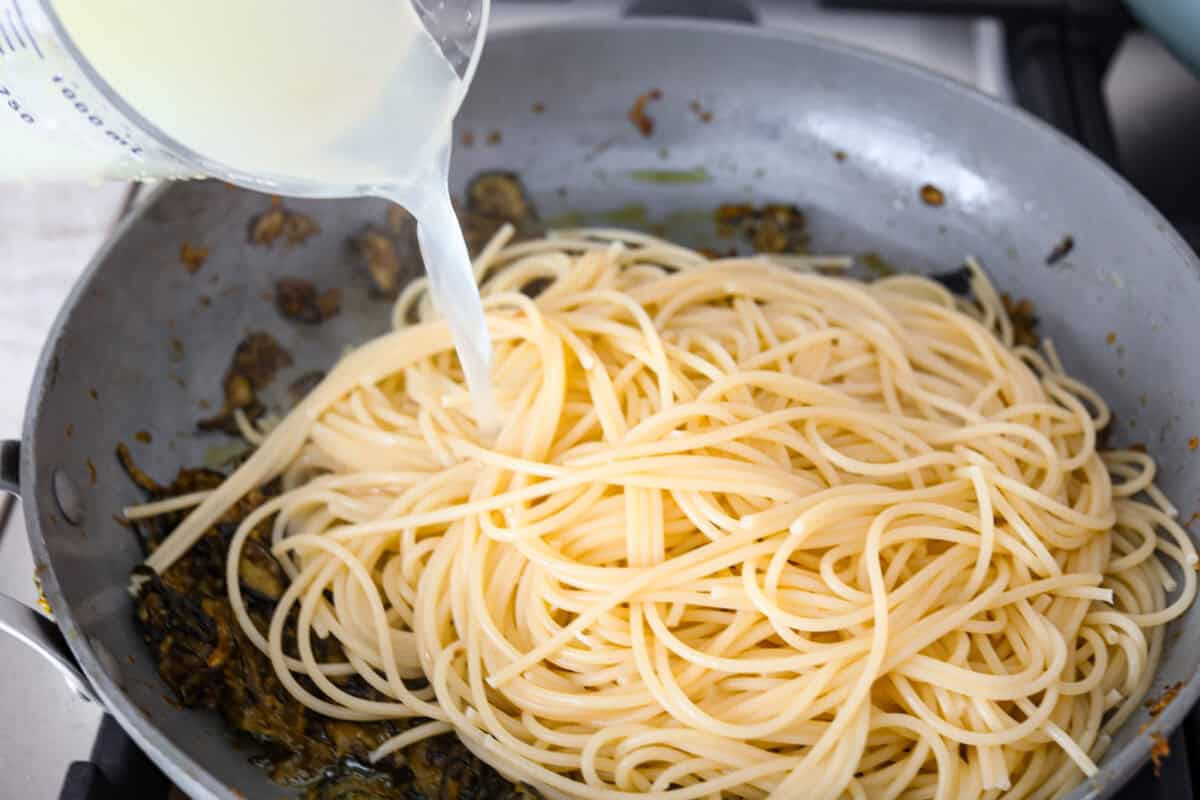 Spaghetti alla Nerano is an unforgettable pasta dish packed with flavor! It has a rich and creamy zucchini sauce infused with garlic, fresh basil, and melted cheese. Sixth photo of the pasta and pasta water added to the skillet.