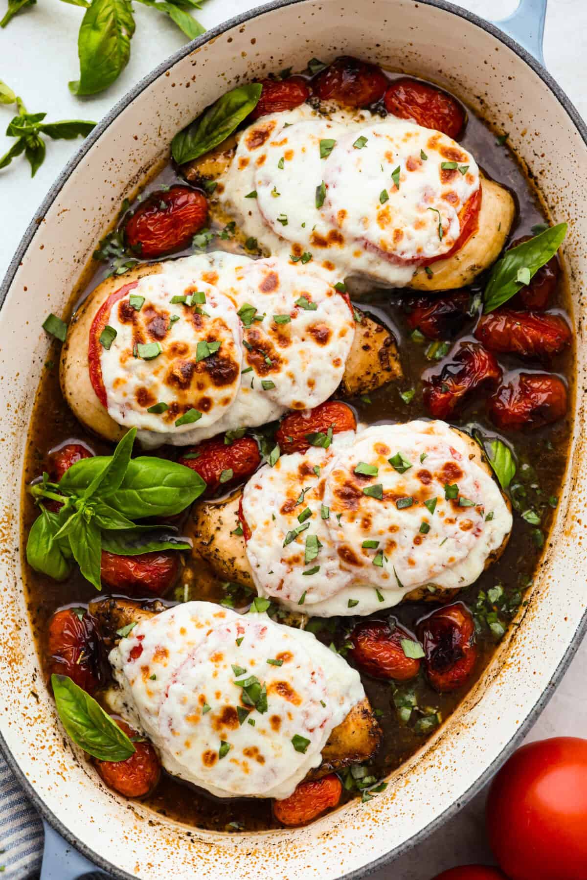 Juicy chicken, melty mozzarella, tomatoes, basil, and balsamic glaze all baked in one pan. Easy, fresh, and so good. Overhead shot of a baking dish with baked caprese chicken.